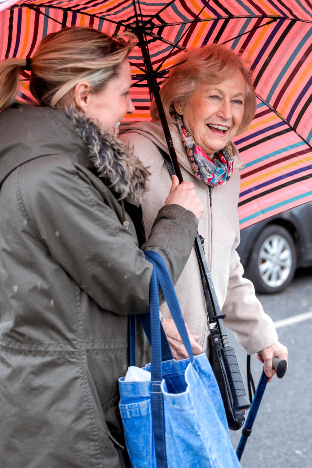 A Papa Pal holding an umbrella for an elderly woman