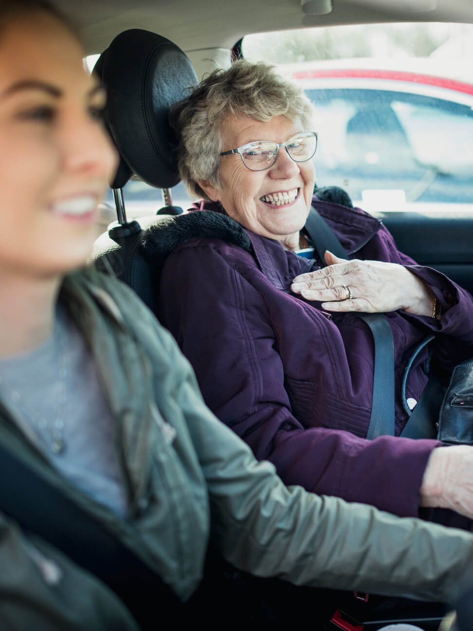 Elderly woman looking happy to be getting driven around by her companion caregiver to run errands