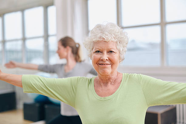 Elderly woman smiling while doing a yoga pose