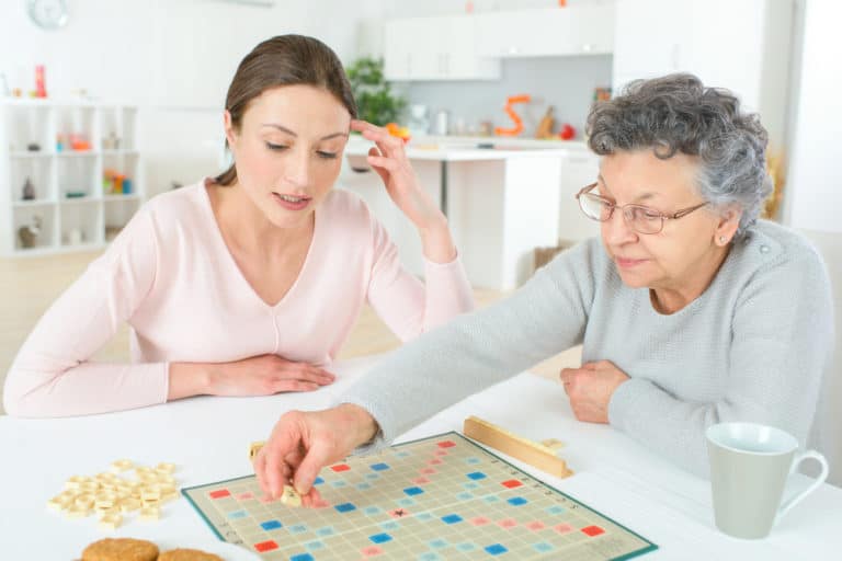 An elderly woman playing Scrabble with her companion caregiver. A game of Scrabble can do wonderful things for the brain and memory.