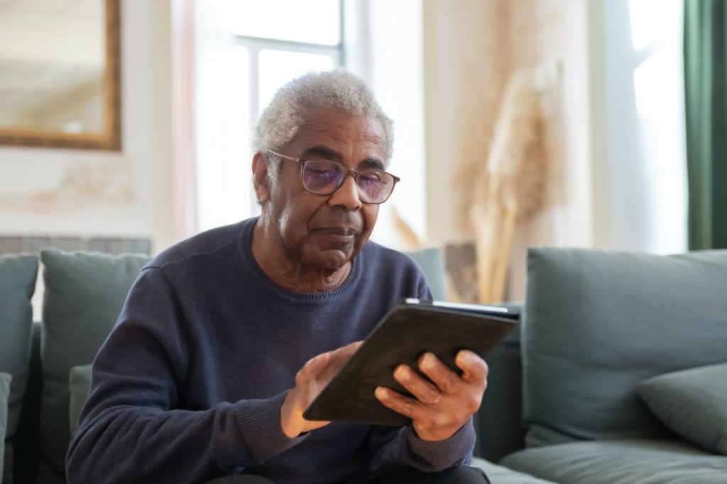 An elderly man playing with his tablet.