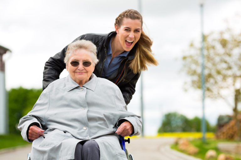 Young woman pushing elderly woman in wheelchair