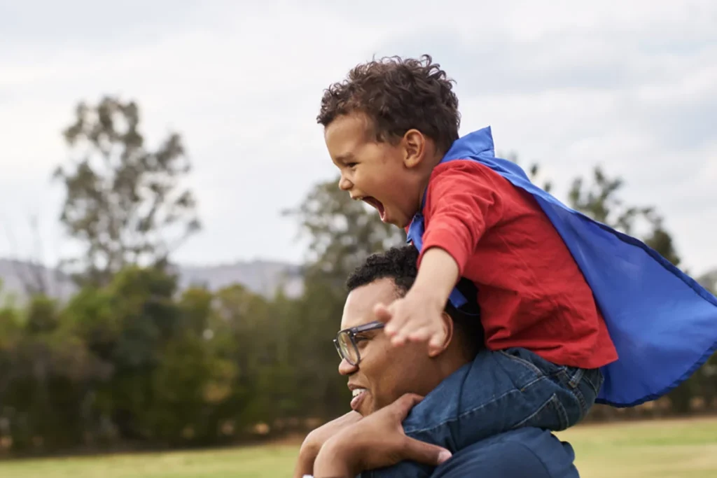 Dad giving his son a piggyback ride outside.