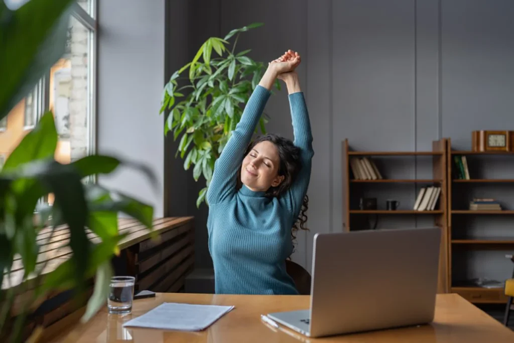 Woman taking time to stretch in the office as part of her unique relaxation employee benefit.