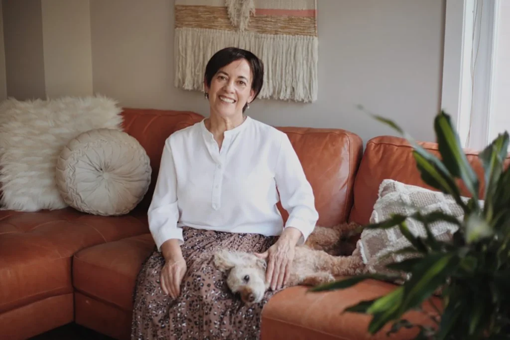 Companion caregiver sitting on a couch with her dog.