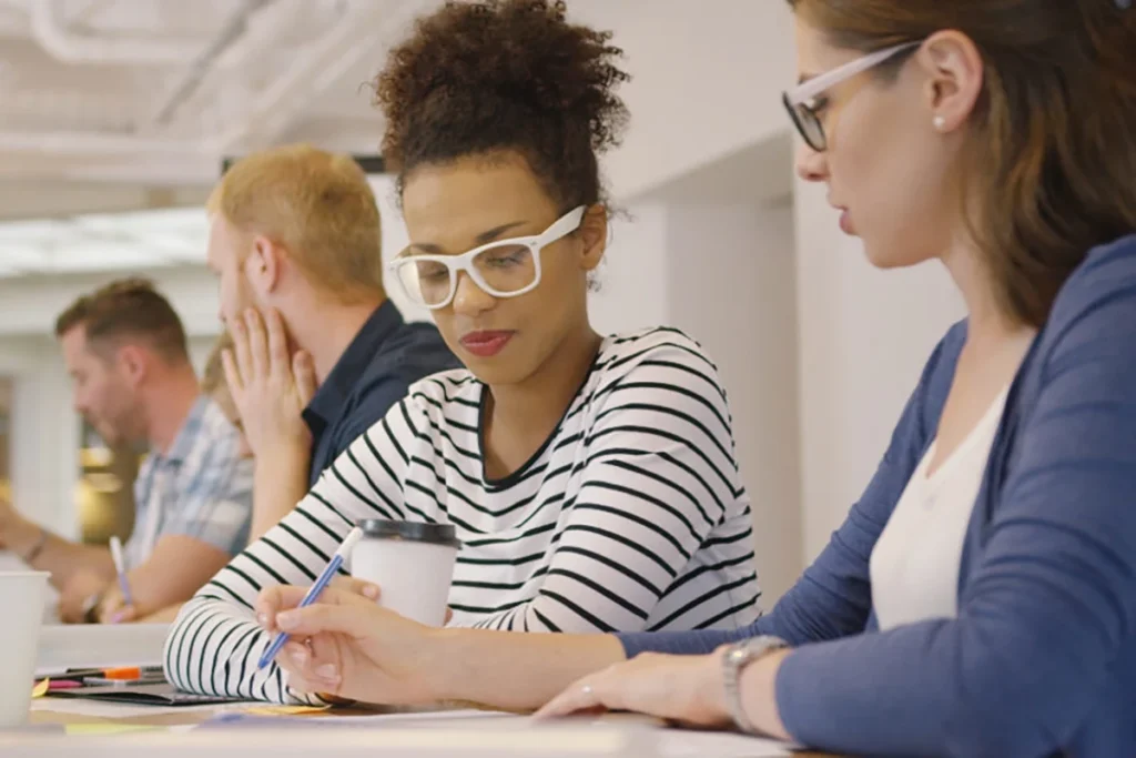 Two female employees looking over an employee benefits guide.