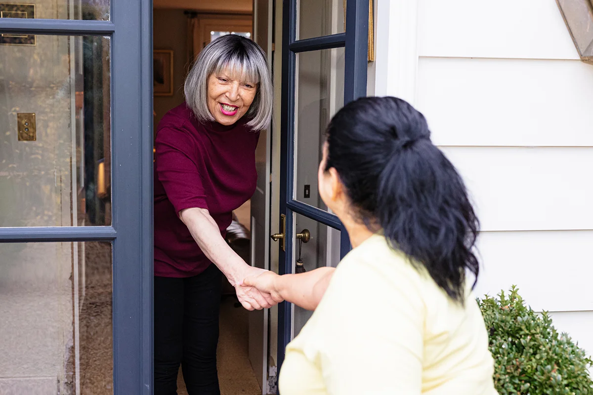 Two women greeting each other at the door.