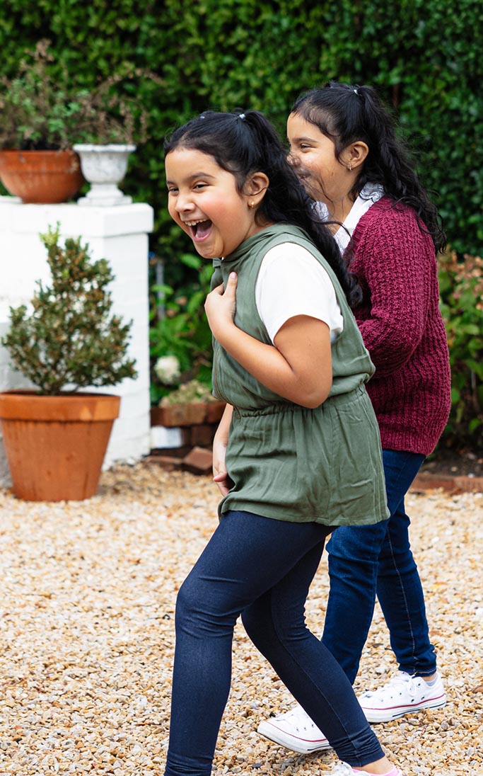 Two young girls laughing while walking.