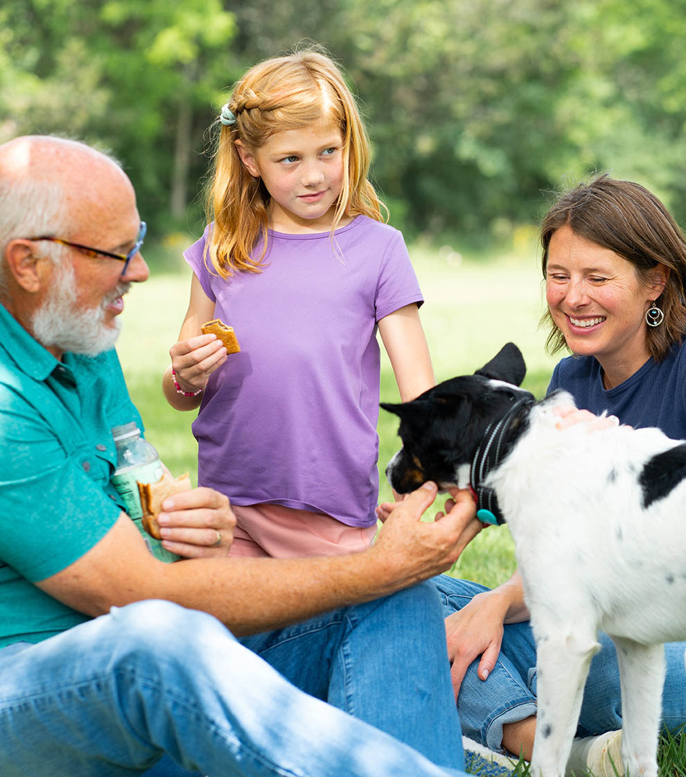 Family playing with their dog in a park.