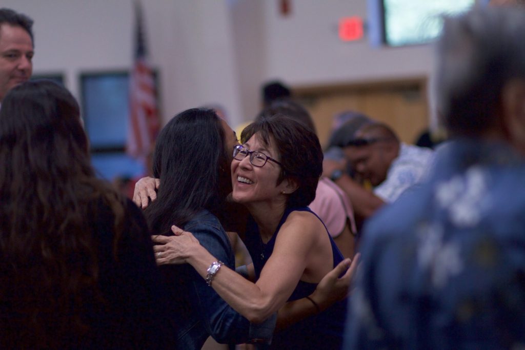 Two women hugging at a community event.