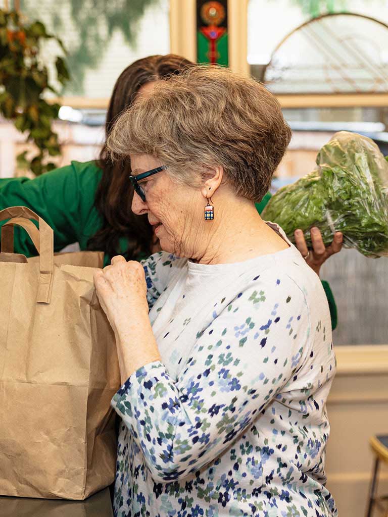 A companion caregiver helping a Papa member to put away groceries.